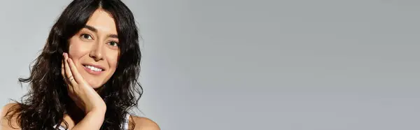 Brunette beauty playfully poses in the studio against a soft grey backdrop. — Stock Photo