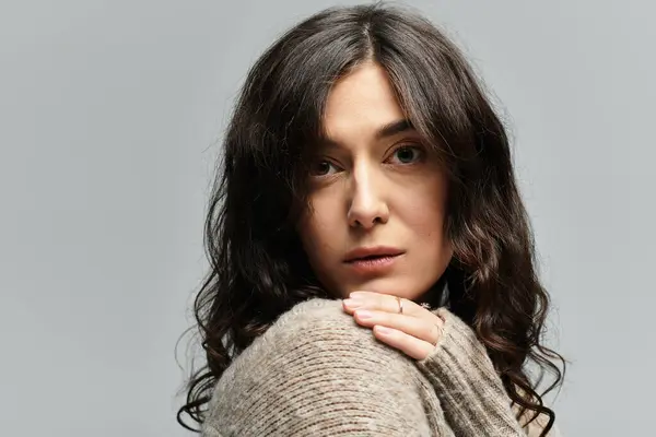 Young brunette woman posing in casual outfit against a soft grey background in studio. — Stock Photo