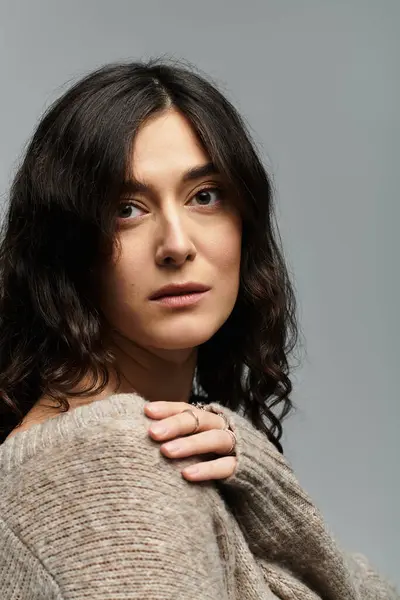 Brunette woman in casual sweater poses thoughtfully in a studio setting. — Stock Photo