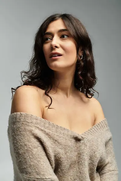 Élégante femme plus la taille dans un pull beige confortable en studio sur fond gris. — Photo de stock
