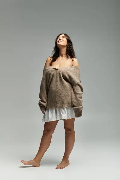 Young plus size woman exudes confidence in a beige sweater against a neutral backdrop. — Stock Photo
