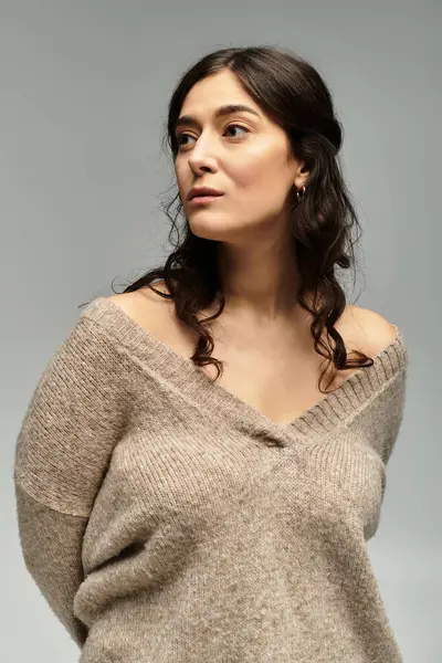 Plus size woman exudes confidence in beige sweater against neutral backdrop. — Stock Photo