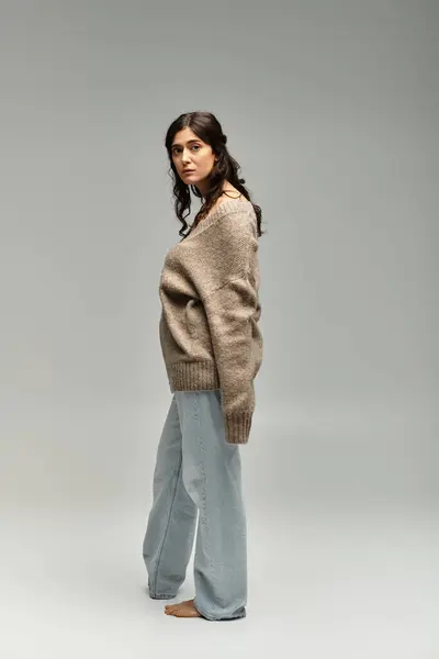 Capturing elegance in a cozy beige sweater against a serene grey backdrop. — Stock Photo