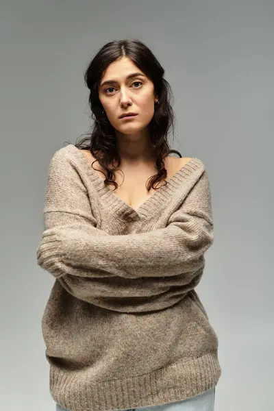 Beautiful plus size woman in beige sweater against grey backdrop in studio setting. — Stock Photo