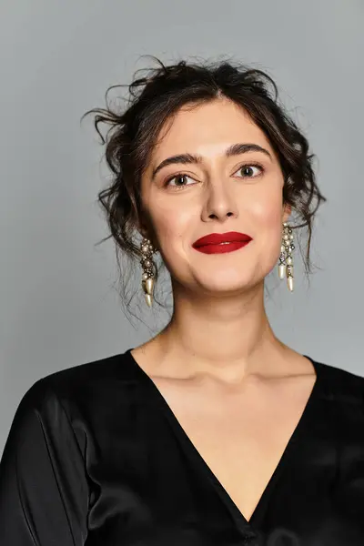 Elegant young woman in stylish black attire poses gracefully in studio setting. — Stock Photo