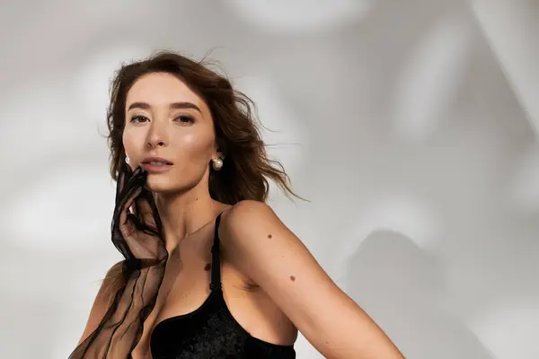 Young beautiful woman showcasing chic lingerie style against a softly lit background. — Stock Photo