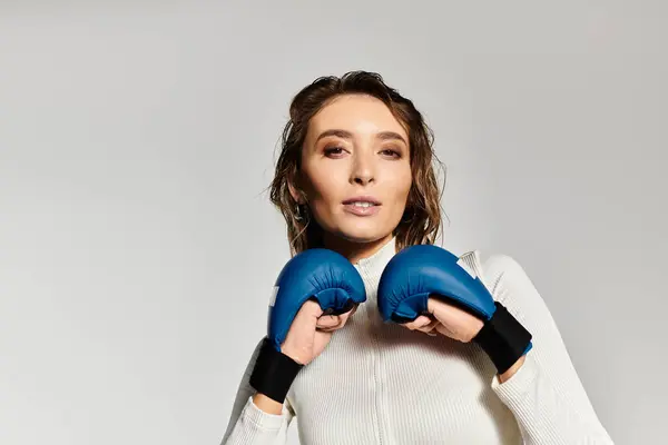 Confident young woman showcases stylish boxing gloves in modern fashion setting. — Stock Photo