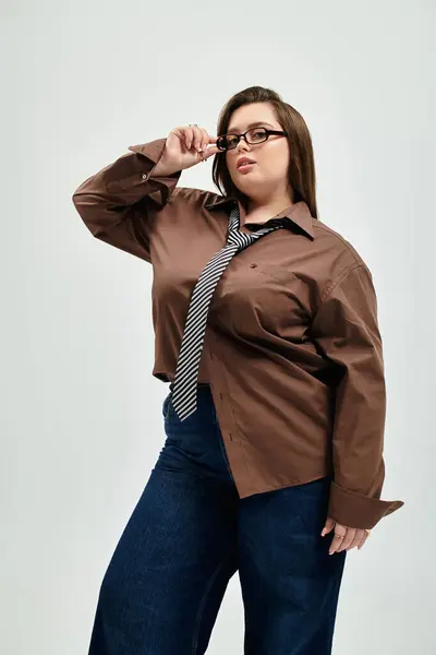 Fiduciosa giovane donna con una bella figura plus size posa in una camicia oversize e cravatta. — Foto stock