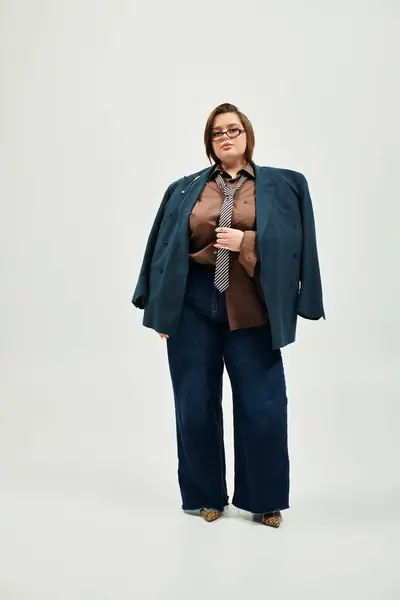 A confident young woman in plus size fashion displays style with a chic oversized blazer and tie. — Photo de stock