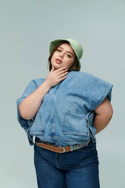A confident plus size woman showcases a trendy denim ensemble, exuding charm and style indoors. — Stock Photo