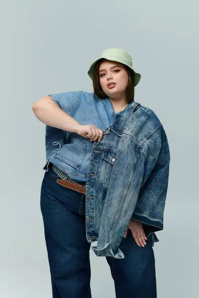 A confident young plus size woman poses stylishly in oversized denim. — Stock Photo