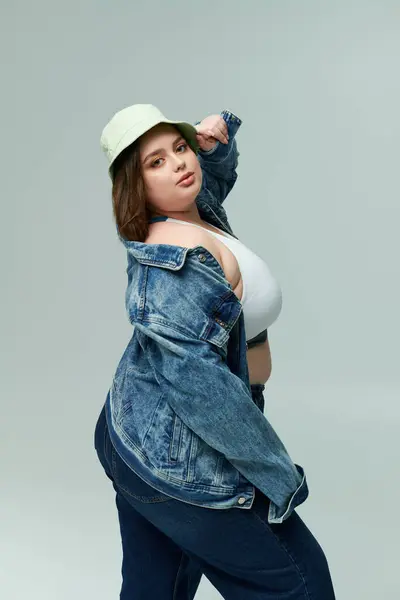 Una bella giovane donna mette in mostra il suo stile e fiducia in una giacca di jeans e cappello a secchio. — Foto stock