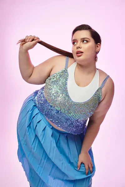 A beautiful young plus size woman poses confidently, holding her hair with a playful expression. — Stock Photo