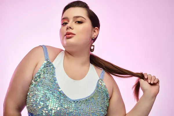 A young plus size woman playfully styles her hair against a vibrant backdrop. — Stock Photo