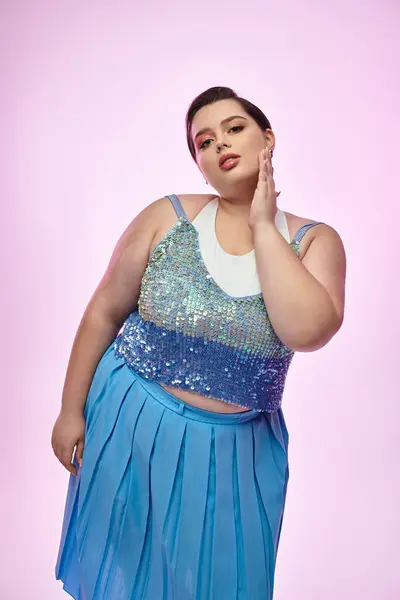 A young plus size woman poses gracefully, showcasing her stunning outfit against a pastel backdrop. — Stock Photo