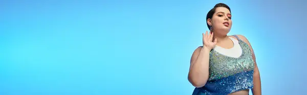 A gorgeous plus size woman playfully poses against a vibrant blue backdrop. — Stock Photo