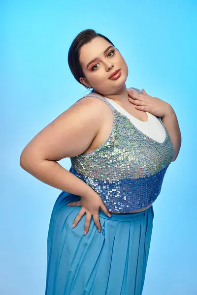 Eine junge Plus-Size-Frau posiert selbstbewusst in einem glitzernden Top und fließendem blauen Rock. — Stockfoto