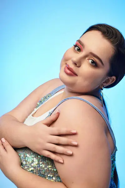 A young and pretty plus size woman poses gracefully in a bright blue studio, showcasing her charm. — Stock Photo