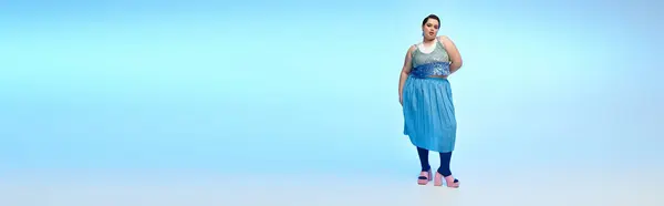 Una bella donna plus size posa elegantemente su uno sfondo blu, ostentando il suo stile. — Foto stock
