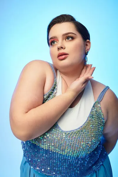 Young and beautiful plus size woman elegantly showcases her style in a mesmerizing blue backdrop. — Stock Photo