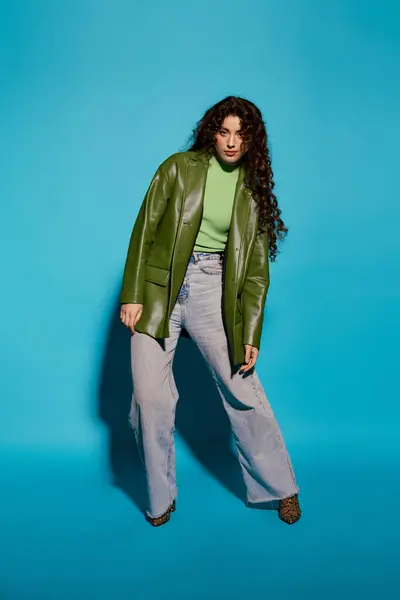 Selbstbewusst und jugendlich steht eine stylische Frau vor leuchtend blauen Farbtönen, während sie ihr Outfit präsentiert. — Stockfoto