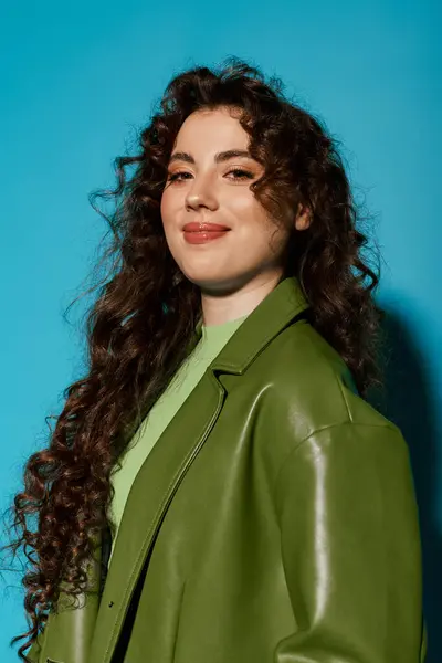 Brightly dressed woman showcases her long curly hair and stylish jacket while smiling warmly. — Stock Photo