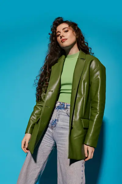 A beautiful young woman showcases her fashionable outfit with a bold green blazer and relaxed jeans. — Stock Photo