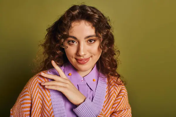 A confident young woman with lively curls showcases her fashionable outfit while smiling charmfully. — Stock Photo