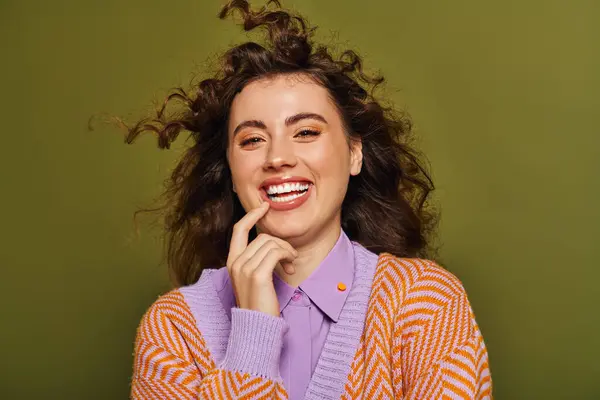 Brightly dressed woman expresses joy with a playful smile and twirling hair, radiating confidence. — Stock Photo