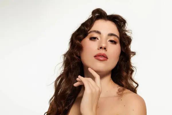 Mujer joven con el pelo rizado posa elegantemente, exudando confianza y estilo sobre un fondo limpio. — Stock Photo
