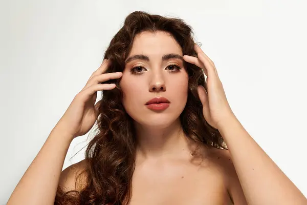 Stylish woman presents a serene expression while gently touching her hair, exuding confidence. — Stock Photo