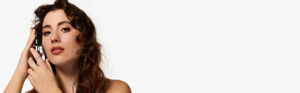 A charming young woman highlights her beauty using a product in a bright studio. — Stock Photo