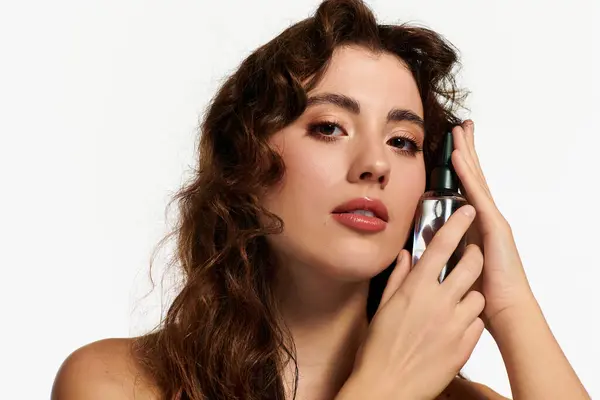 Une jeune femme à la mode tient un produit de beauté près de son visage, exsudant charme et élégance. — Photo de stock