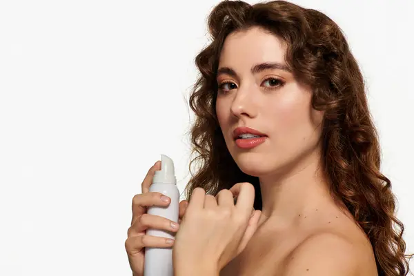 A young and stylish woman applies an elegant beauty product, radiating confidence in a bright space. — Stock Photo
