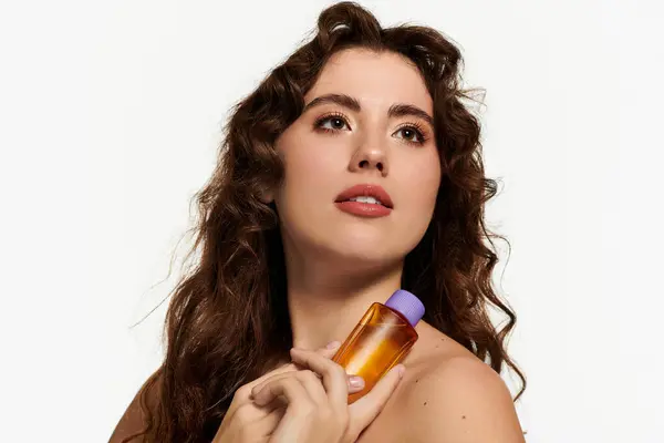 Confident young woman holds beauty product close, radiating elegance and style in a bright space — Stock Photo