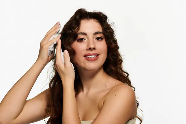 Young woman applies cream to refresh her curls and enjoy a moment of self care. — Stock Photo