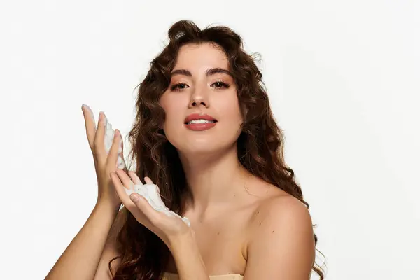 A beautiful young woman enjoys applying a luxurious skincare product, glowing with confidence. — Stock Photo