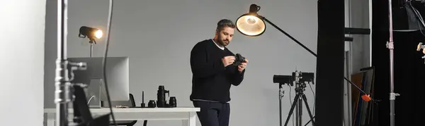 A skilled professional examines his camera equipment in a stylish studio filled with lighting. — стоковое фото