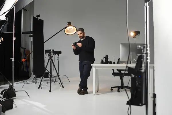 Photographer engages with camera gear in a sleek, inspiring studio. — Stock Photo