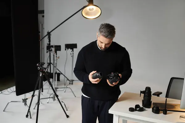A focused individual inspects camera lenses in a modern studio, prepping for a shoot. — Stock Photo