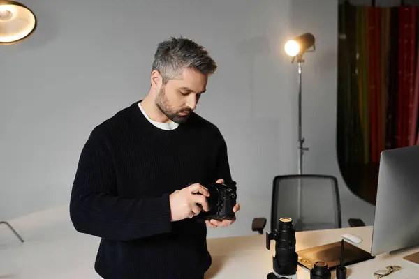 Focused individual prepares his camera while surrounded by professional gear in a bright studio. — Stock Photo
