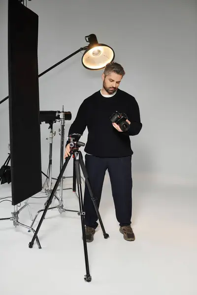 A man focused on preparing his camera in a well lit photography studio, showcasing his dedication. — Stock Photo