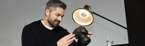 Un homme habile examine les réglages de la caméra dans un studio élégant rempli d'un éclairage doux. — Photo de stock