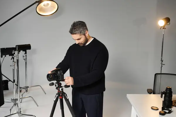 A skilled individual prepares his camera and tripod in a spacious, well lit studio environment. — Stock Photo
