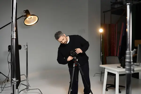 A skilled man adjusts his camera settings in a well equipped studio, preparing for a creative shoot. — Stock Photo