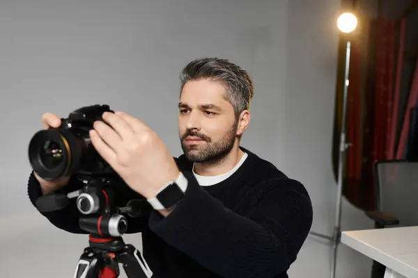 Чоловік зосереджений на налаштуванні обладнання фотоапарата під час підготовки до фотосесії. — стокове фото