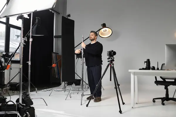 A dedicated man adjusts lighting gear in a stylish photography studio during a busy workday. — Stock Photo