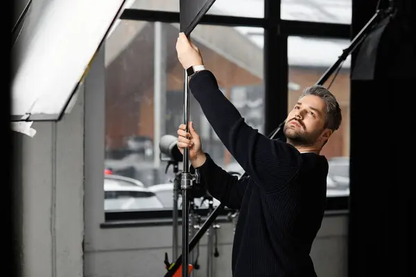 Un professionista esperto sta installando l'attrezzatura di illuminazione mentre si concentra sul compito a portata di mano in uno studio. — Foto stock