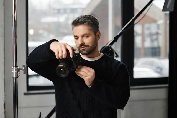 A skilled professional inspects his camera while preparing for a creative shoot in a modern studio. — Stock Photo