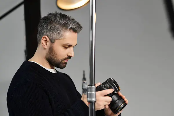 Skilled individual examines camera gear while getting ready for an indoor shoot in a studio setting. — Stock Photo